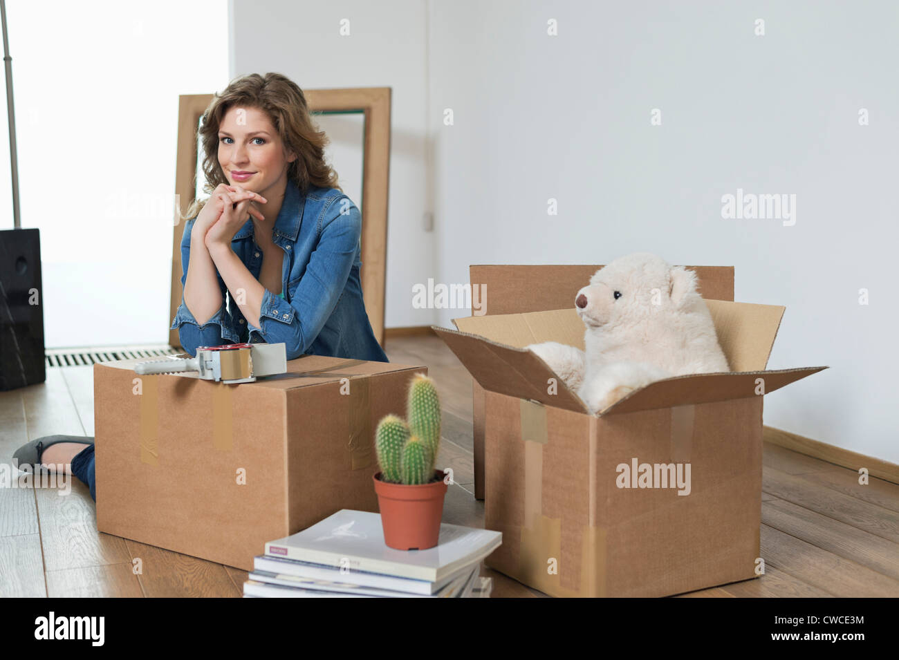 Woman leaning on a cardboard box and smiling Stock Photo - Alamy