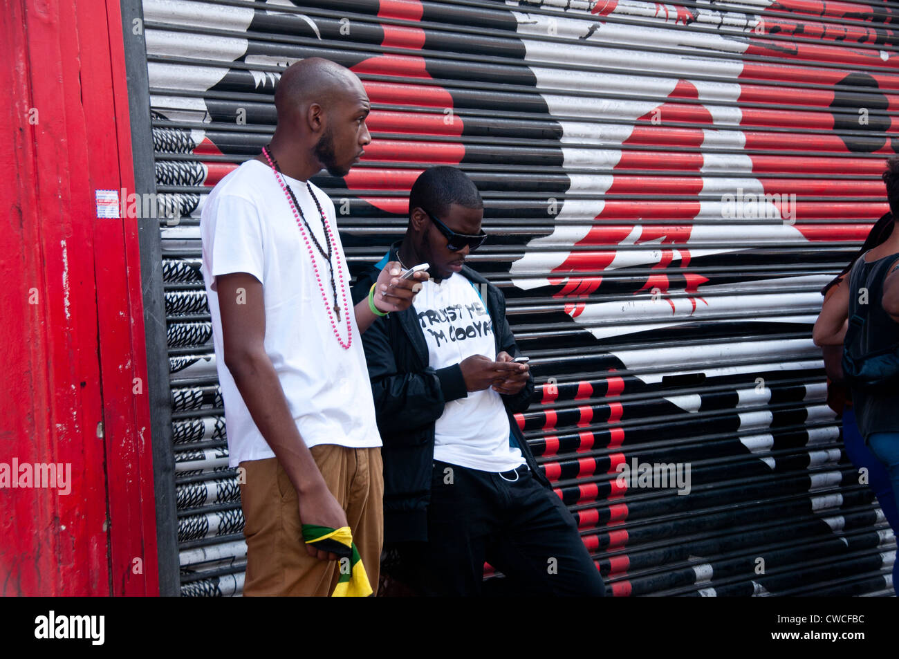 Two men texting on mobile phones in street in Brixton South London ...