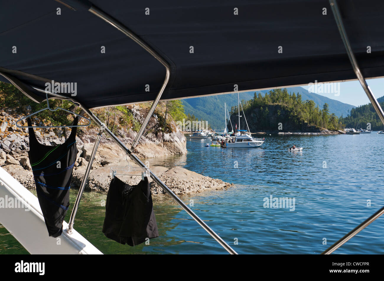 A wet bathing suit and shorts hang to dry inside a boat anchored in the warm waters of Pendrell Sound on a beautiful summer day. Stock Photo