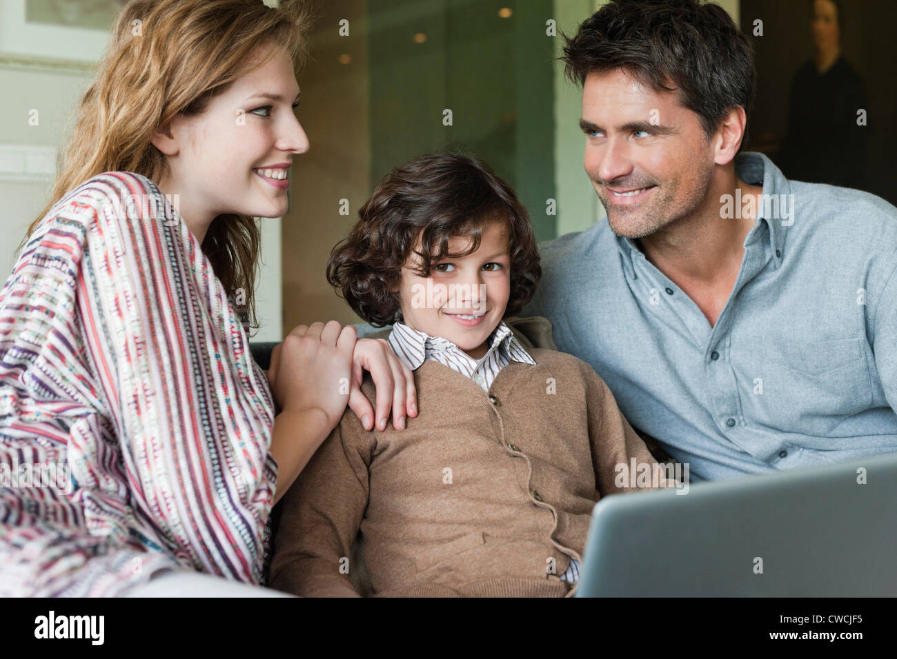 Boy using a laptop with his parents at home Stock Photo - Alamy