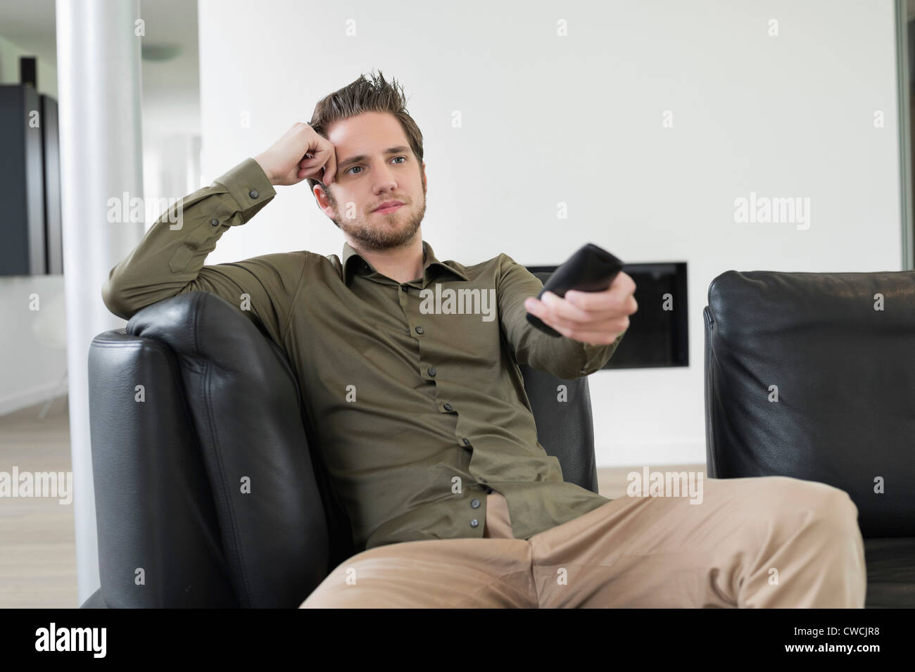 Man using remote control while watching television Stock Photo - Alamy