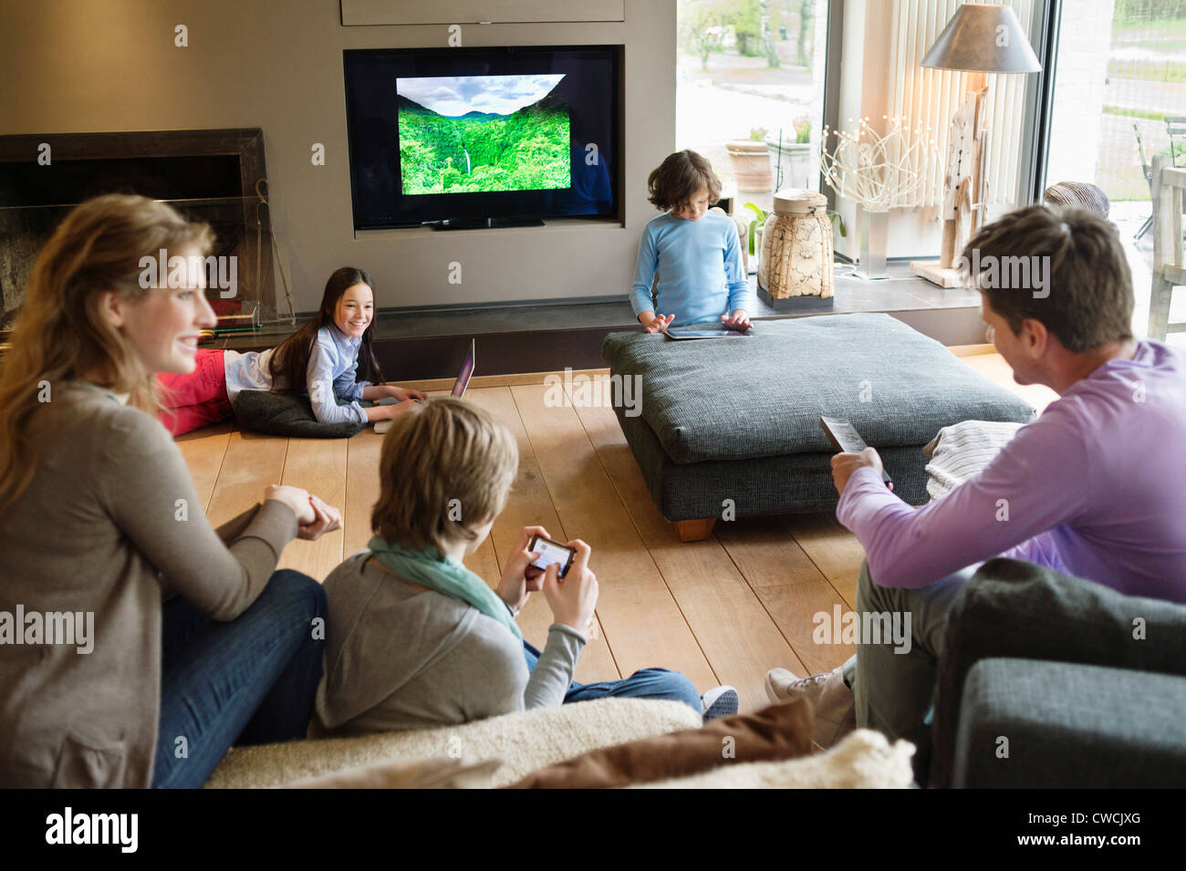 Family using electronic gadgets in a living room Stock Photo Alamy