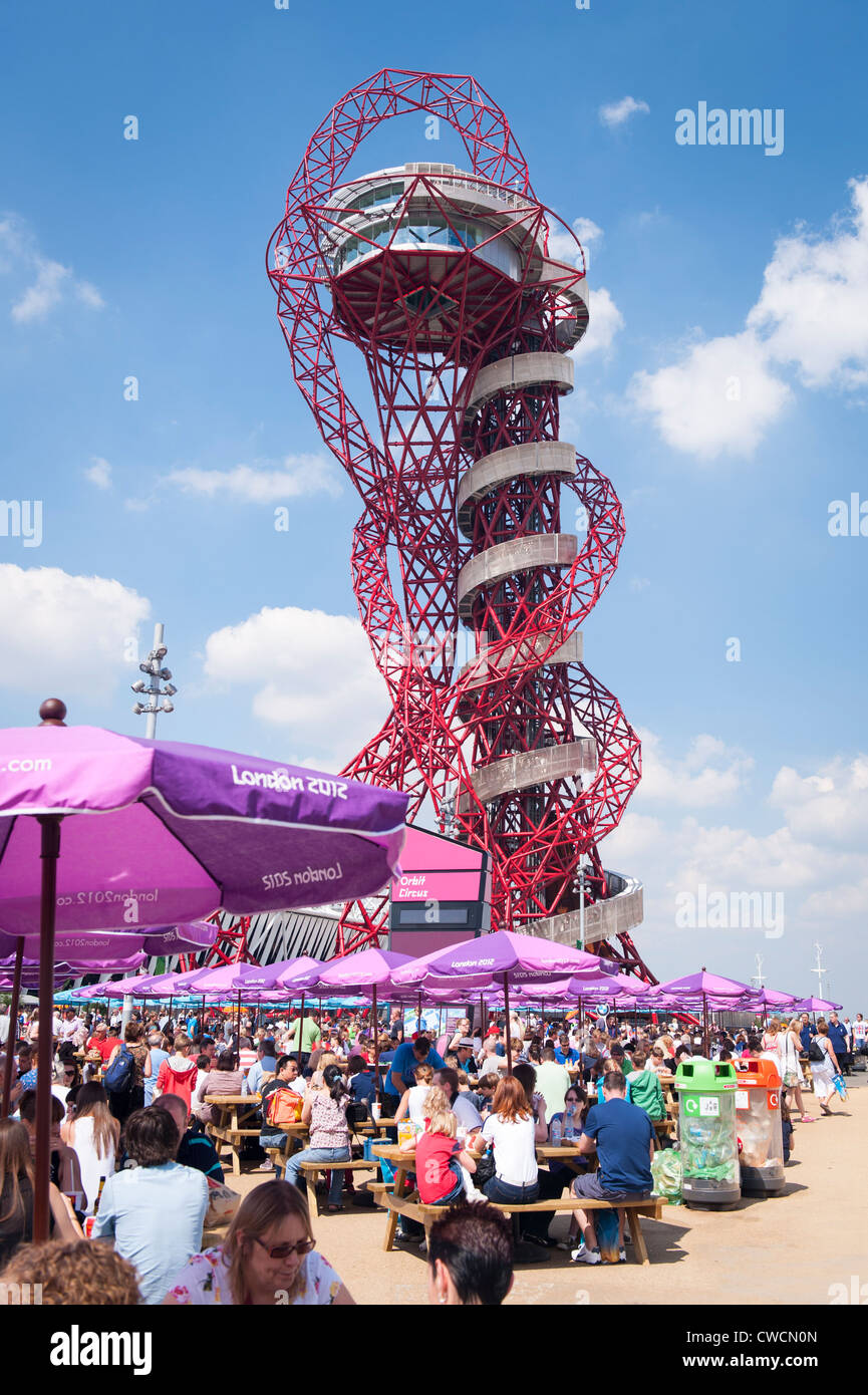 London 2012 Stratford Olympic Park the Anish Kapoor sculpture statue art work Orbit towers over crowds people 114 metres Stock Photo