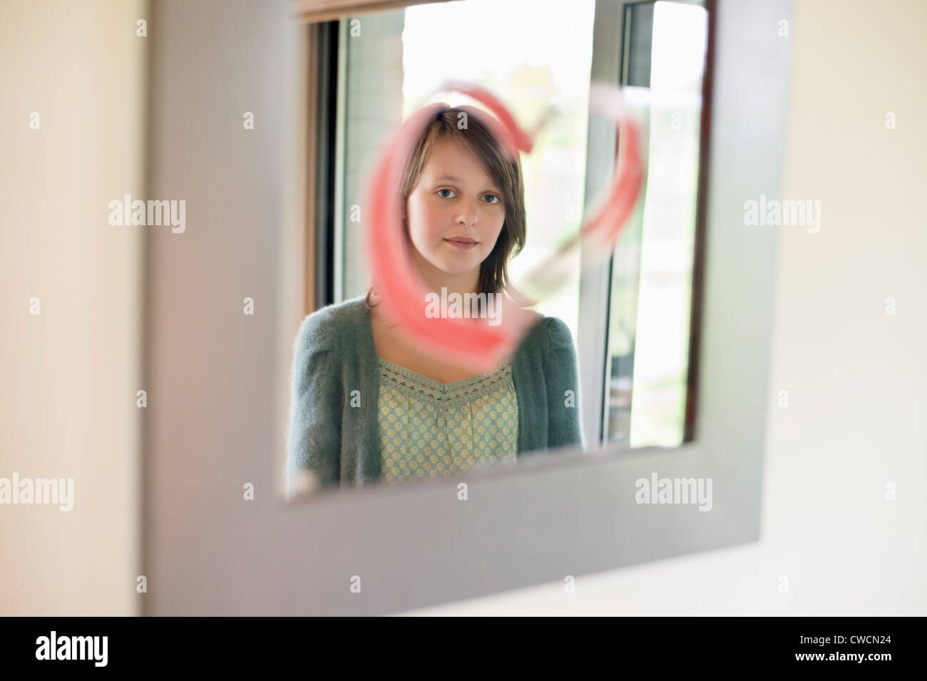 Girl looking at reflection in mirror decorated with heart shape Stock ...