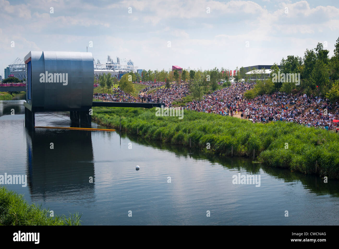 London 2012 Stratford Olympic Park BA British Airways Park Live West venue giant screen screens spectators grass bank water Stock Photo