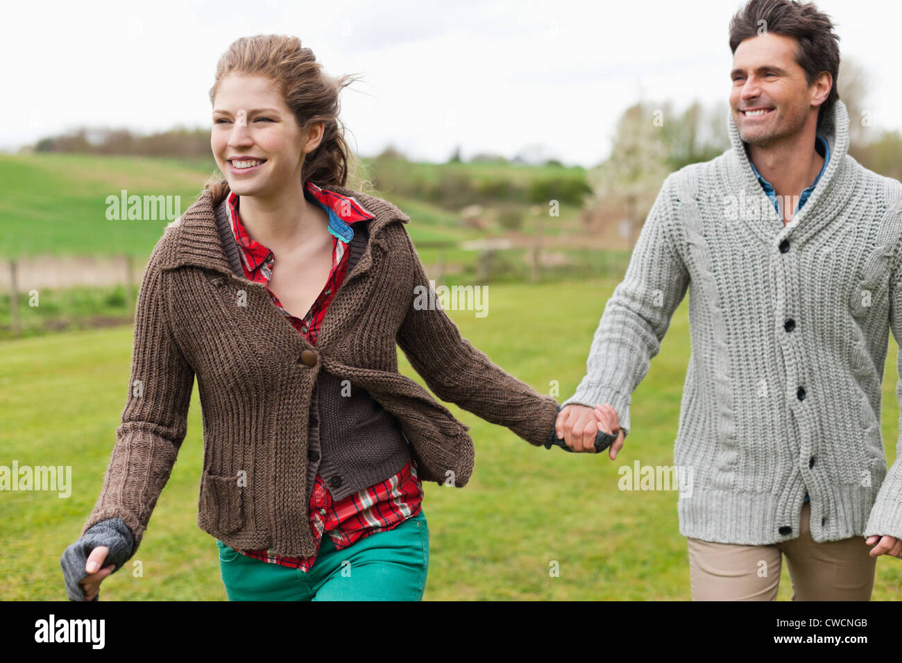 Couple holding hands in a field Stock Photo - Alamy