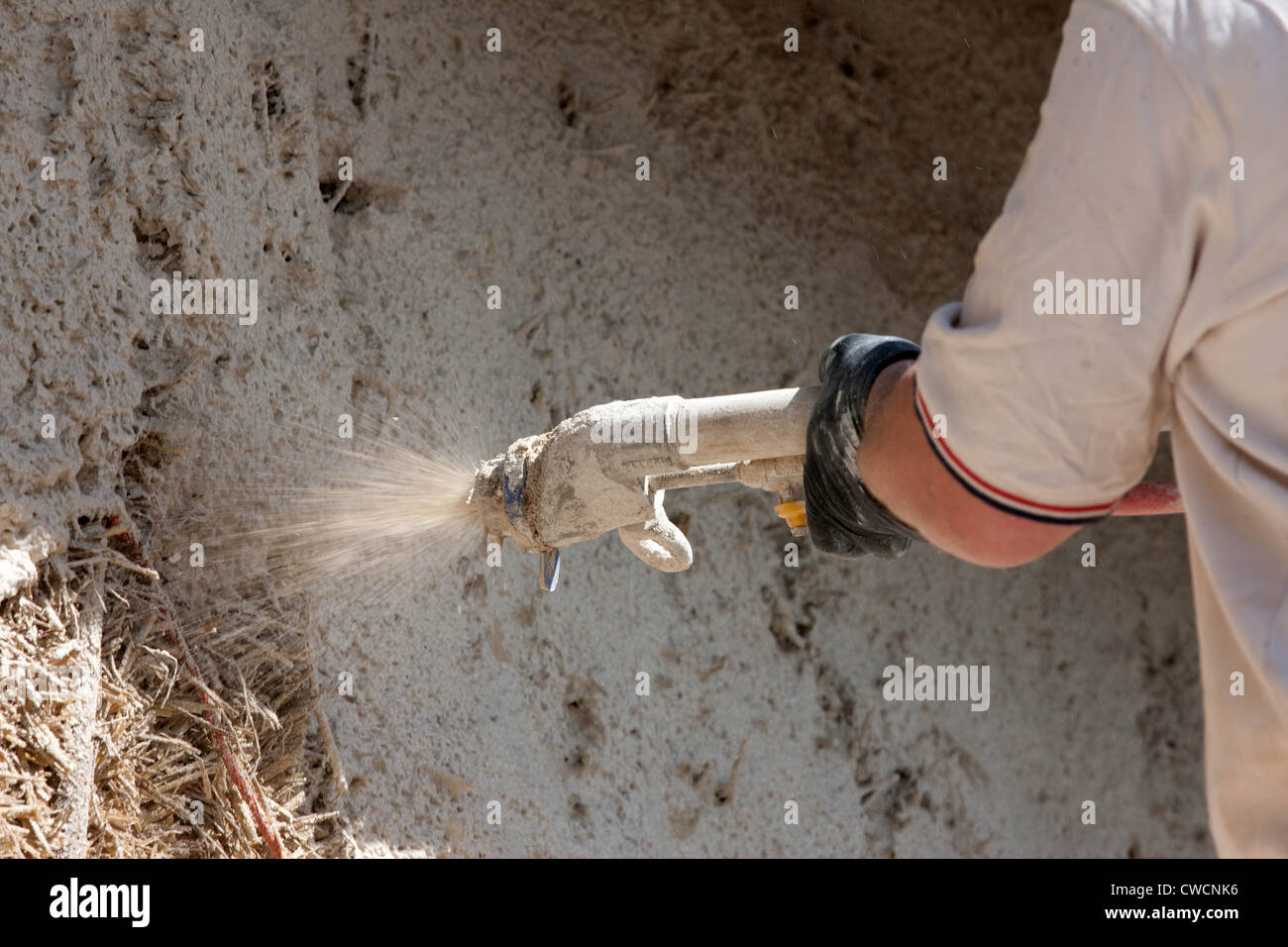 Render being applied to a straw covered building Stock Photo