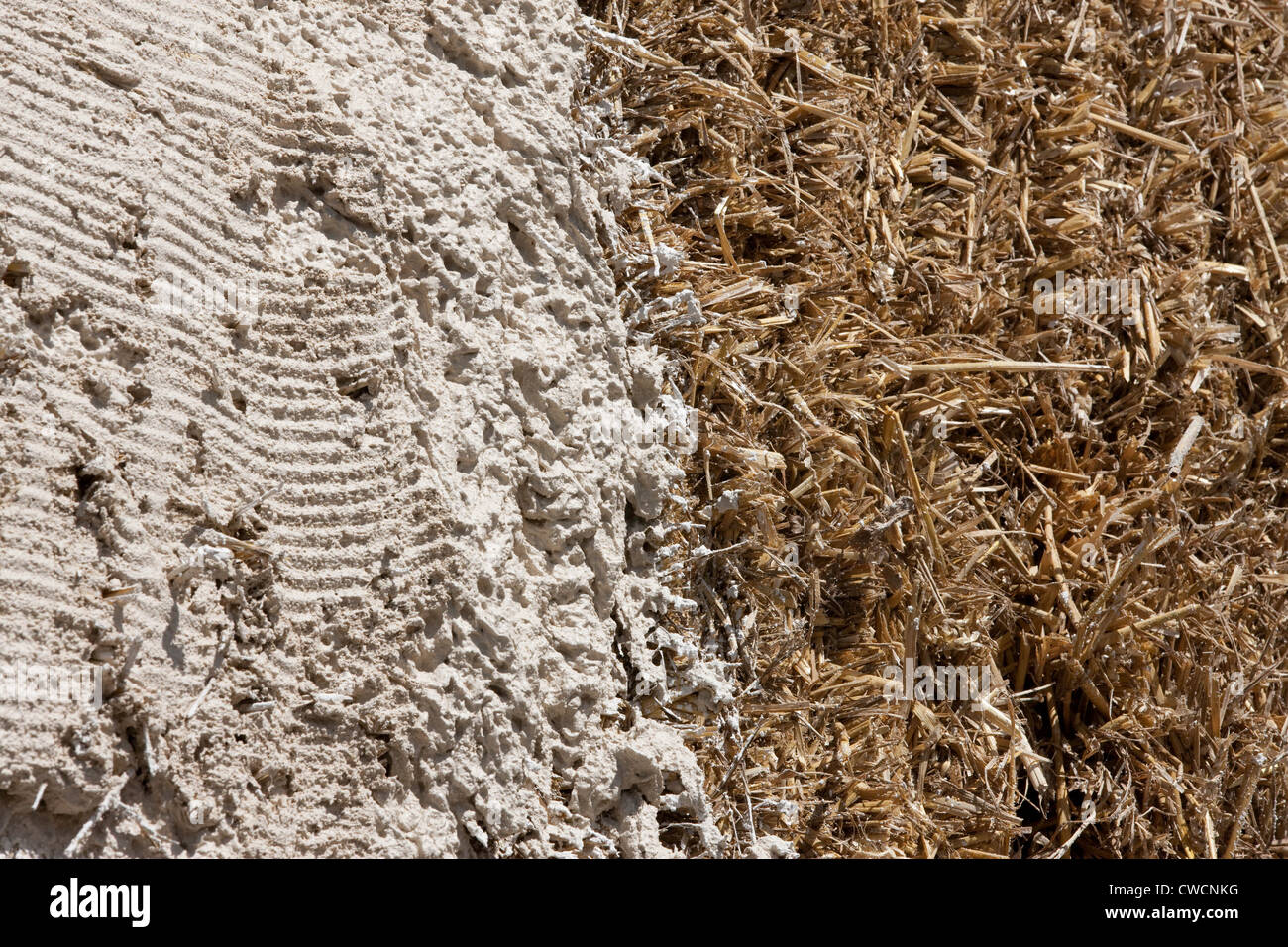 Render being applied to a straw covered building Stock Photo