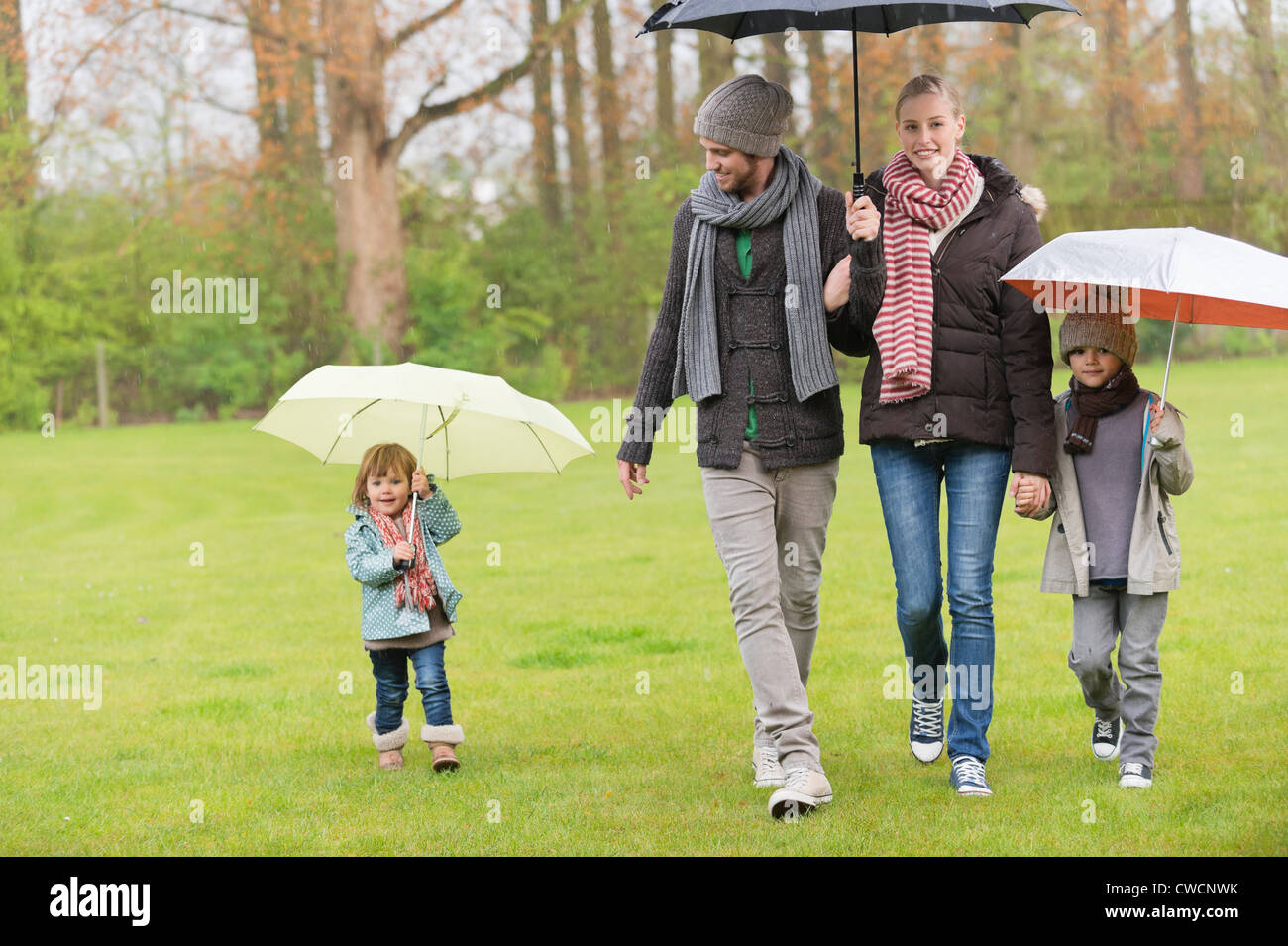 Family walking with umbrellas in a park Stock Photo Alamy