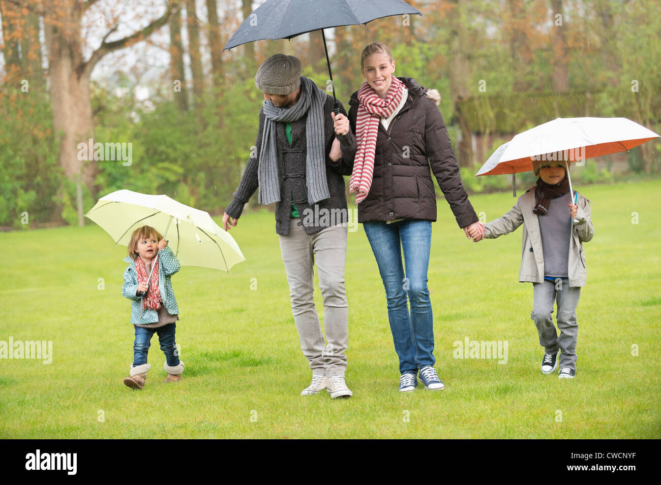 Family walking with umbrellas in a park Stock Photo - Alamy