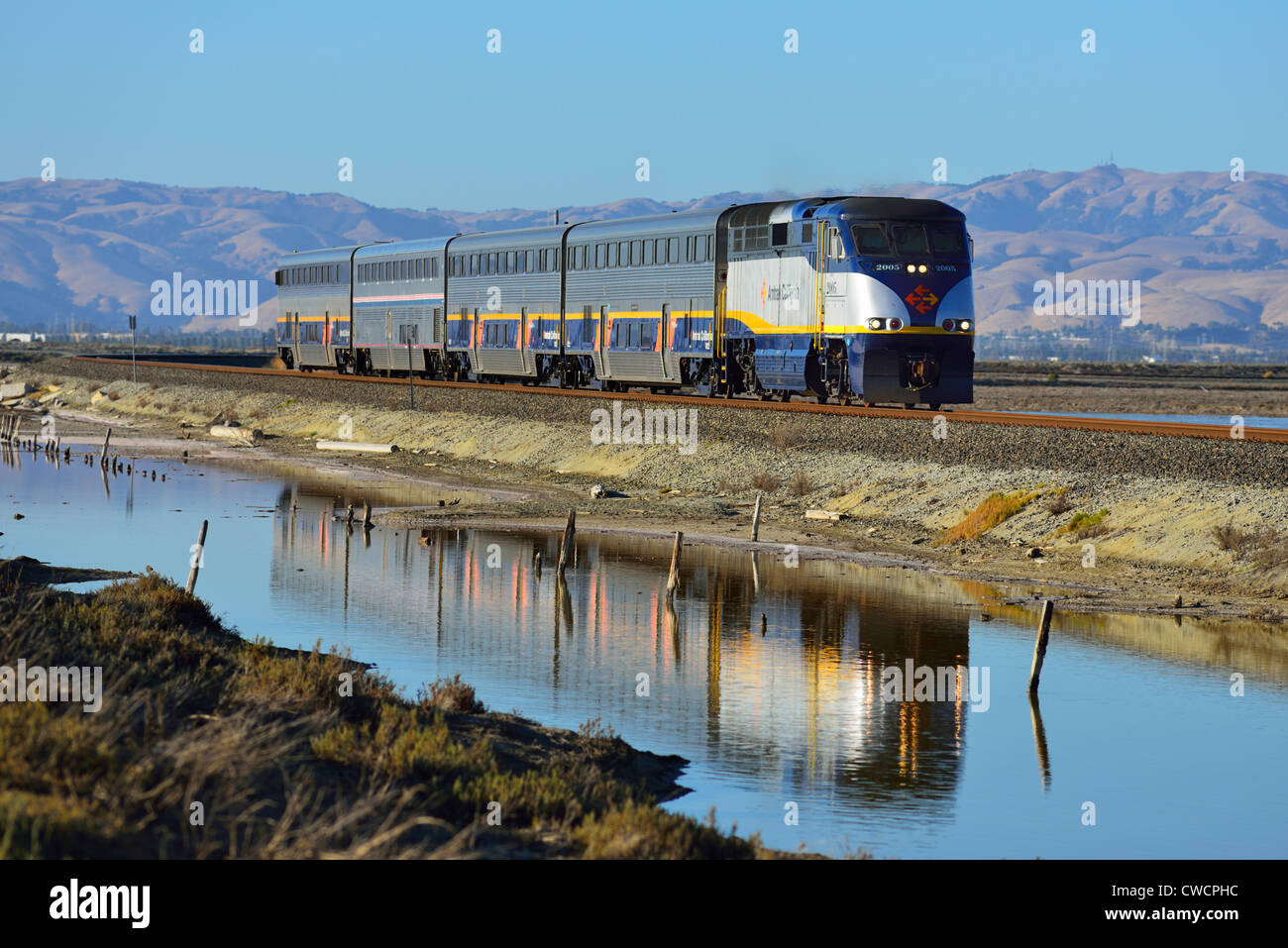An Amtrak train crossing the Alviso Marina County Park during sunset, San Jose CA Stock Photo