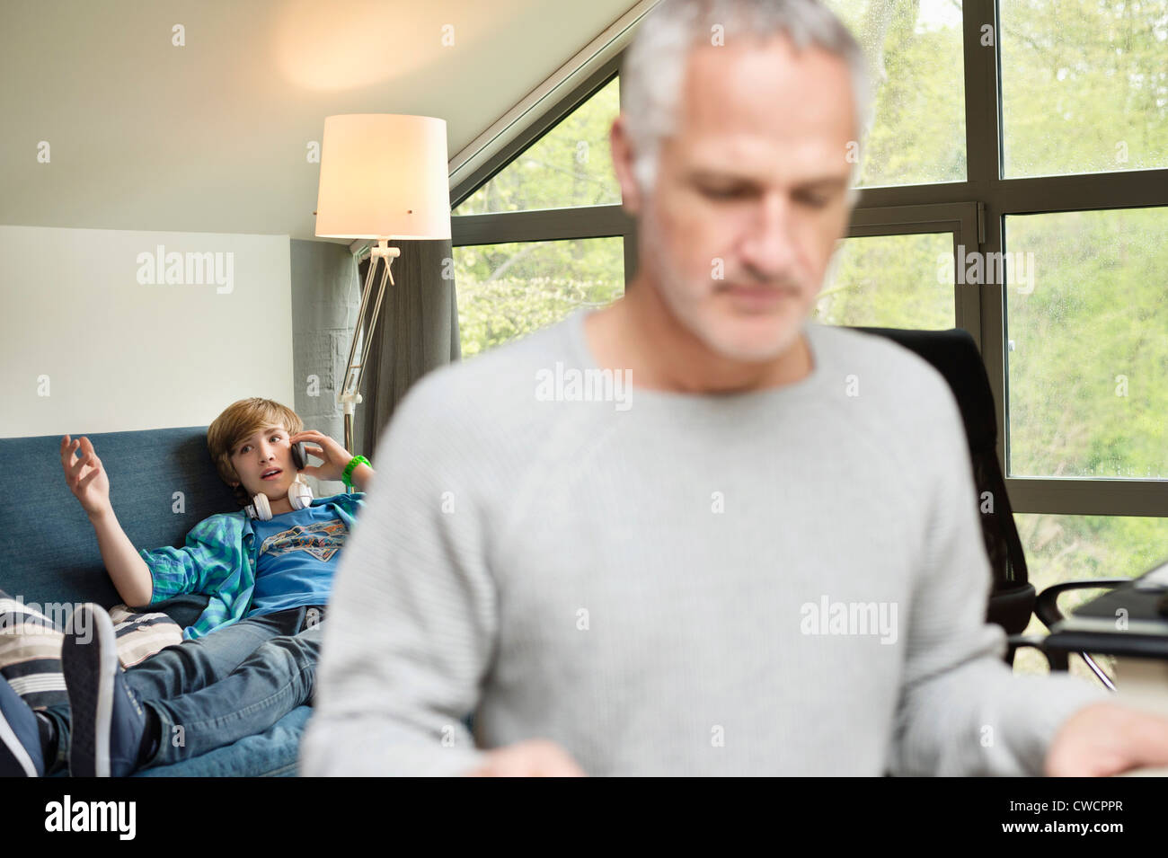 Teenage son listening music in headphones or playing online games ignoring  his mother Stock Photo - Alamy