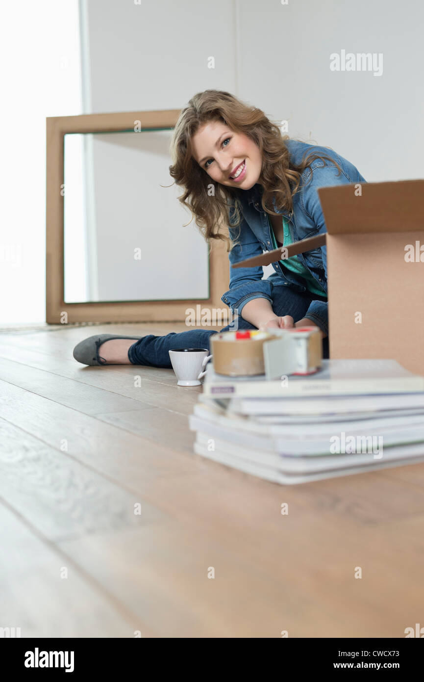 Woman sitting near cardboard boxes and smiling Stock Photo - Alamy