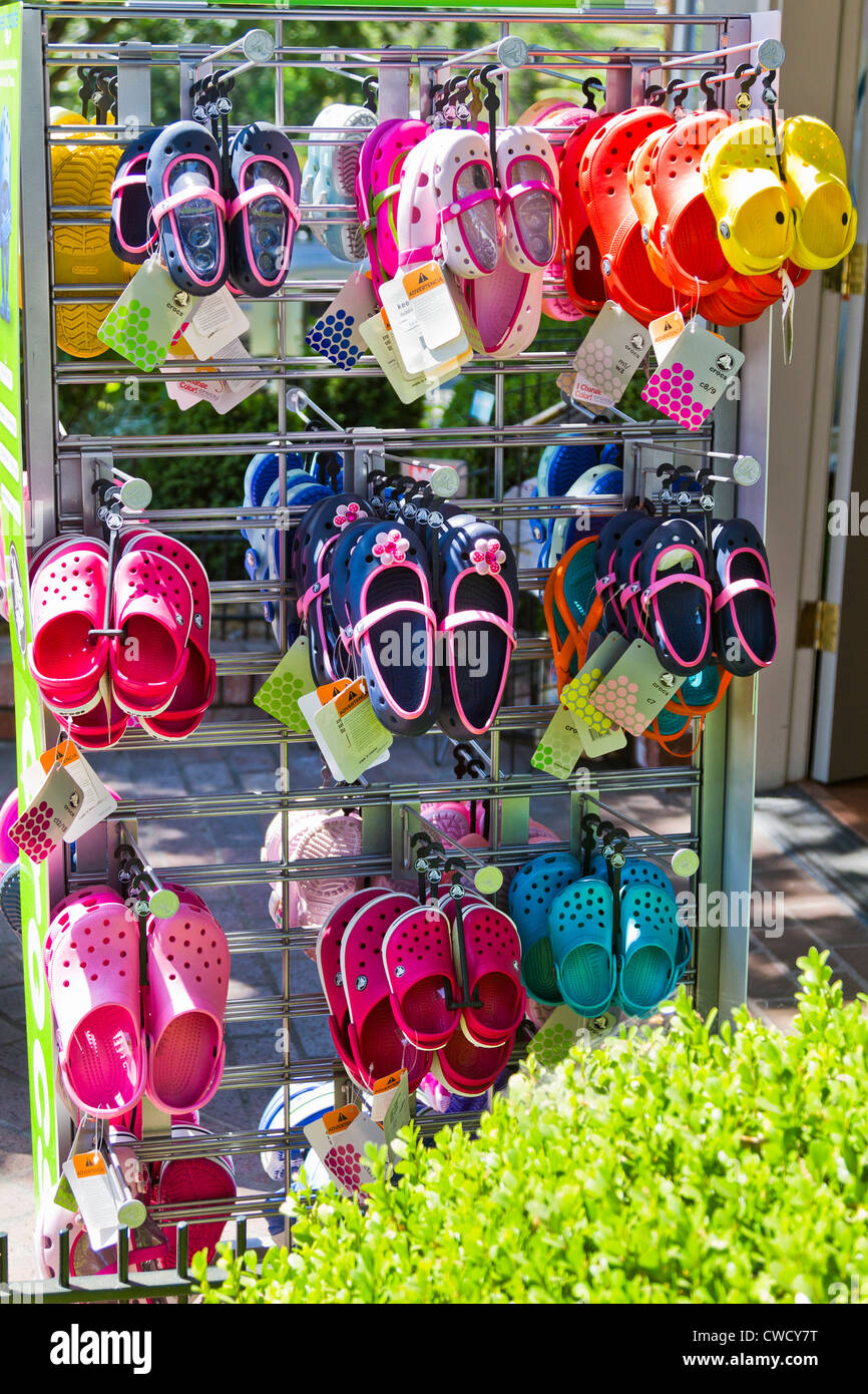 Colorful shoes are displayed for sale on the sidewalk in front of a