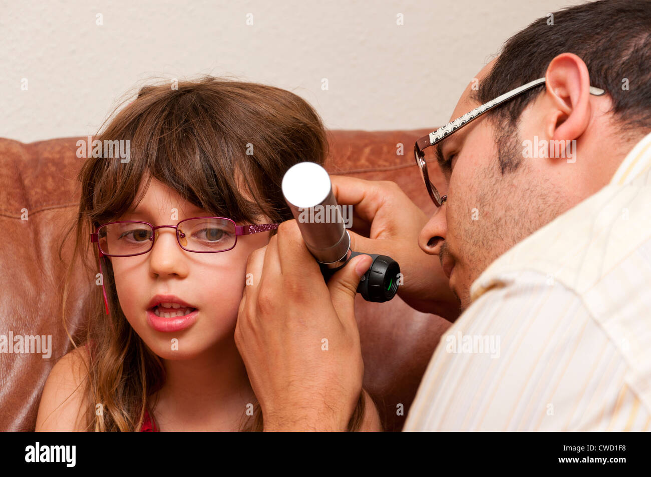 Doctor on a home visit examining a child with a otoscope. Stock Photo