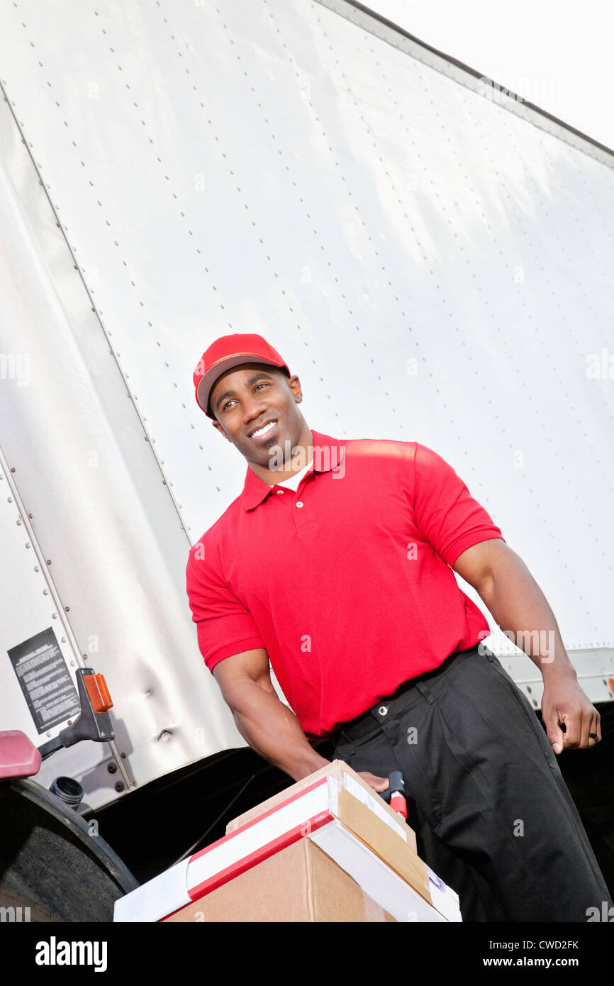 Happy African American delivery man pushing handtruck Stock Photo