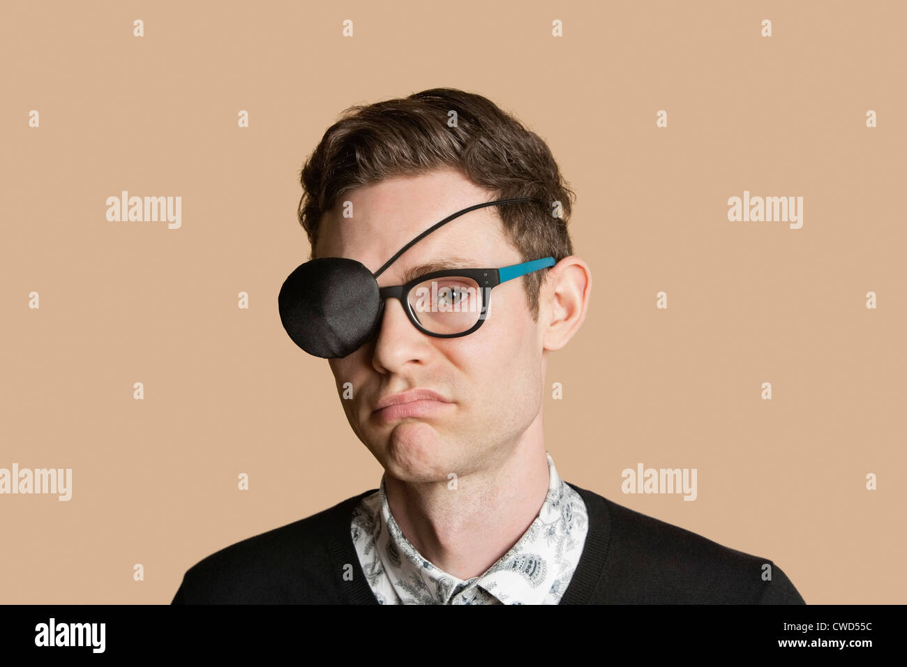 Portrait of a man wearing eye patch on glasses over colored background Stock Photo