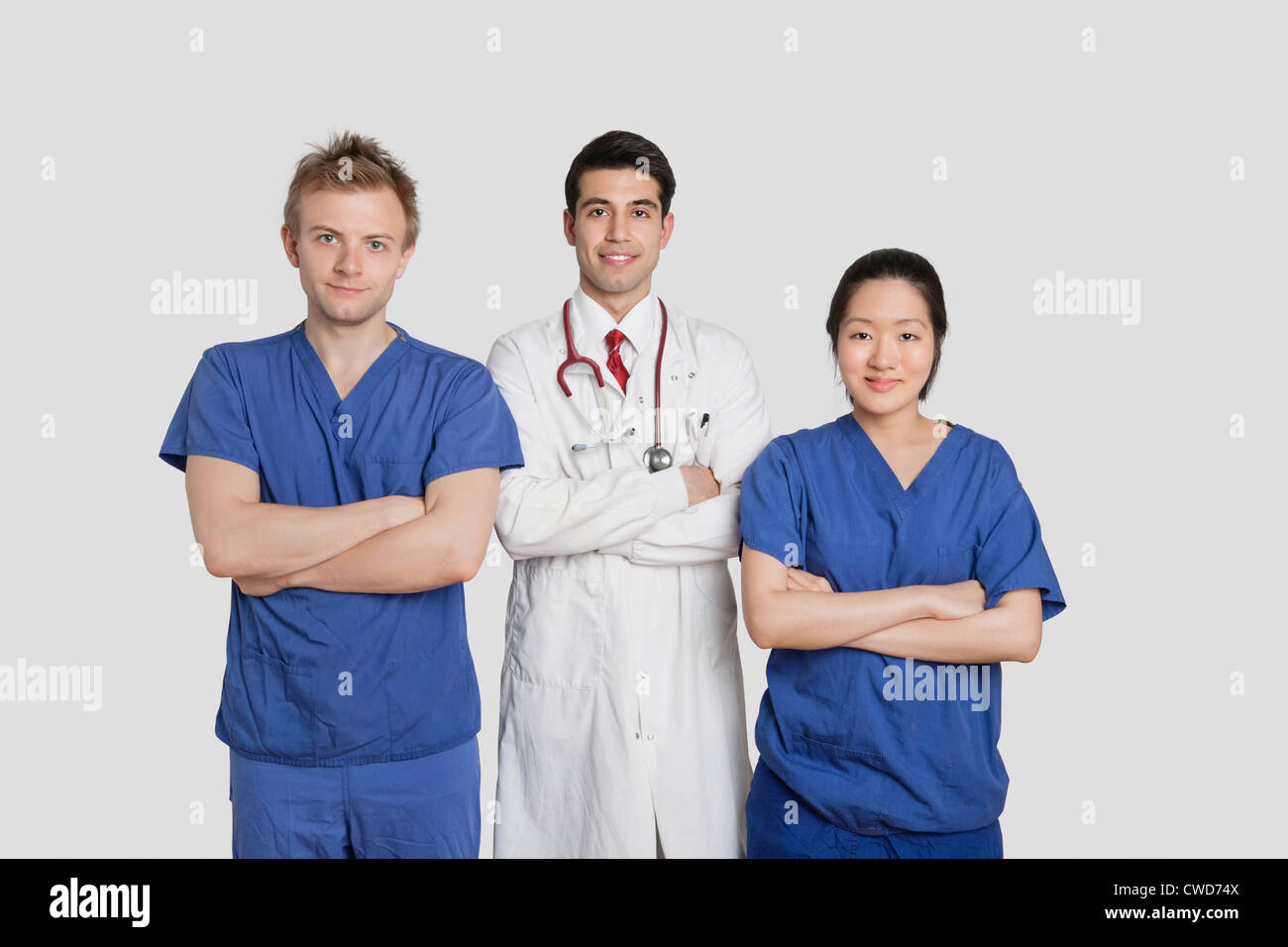 Portrait of diverse healthcare workers standing with hands folded over gray background Stock Photo