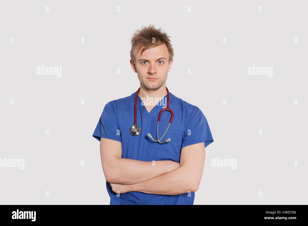 Portrait of a serious male surgeon standing with arms crossed over gray background Stock Photo