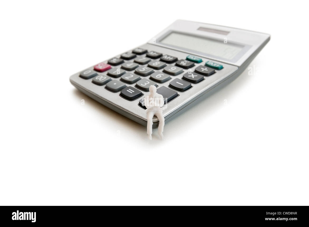 A small dummy figure sitting on a calculator over white background Stock Photo
