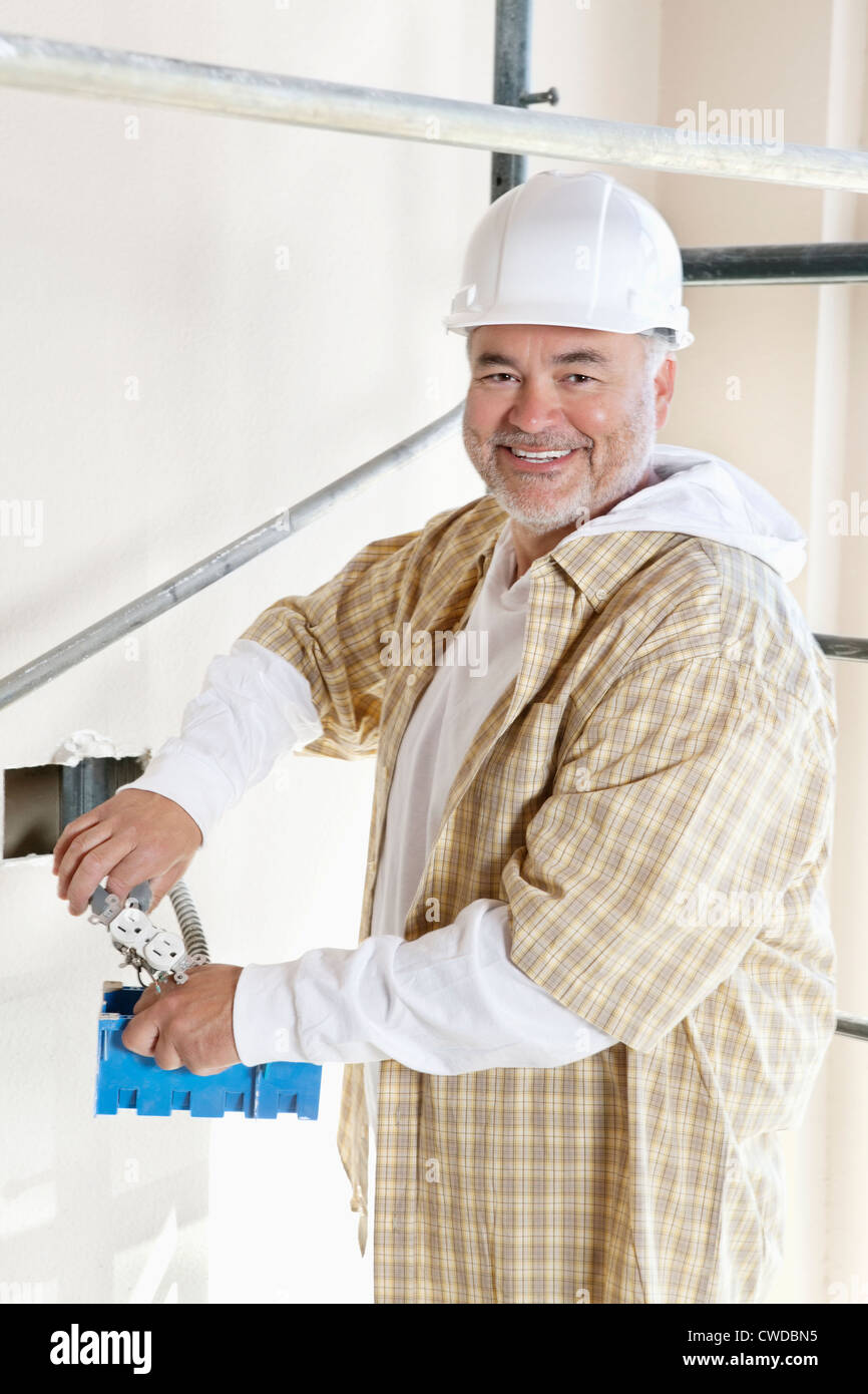 Portrait of a cheerful mature man holding construction equipment Stock Photo