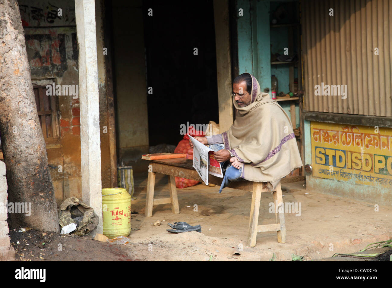 Man reading the newspaper while ignoring everything around him, in Baruipur, West Bengal, India on January 13, 2009. Stock Photo