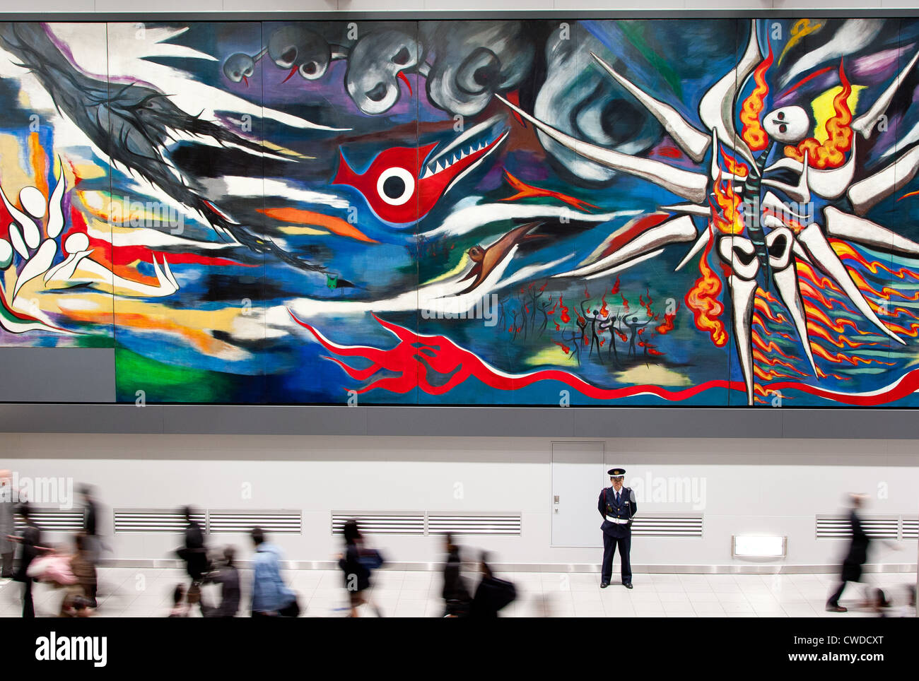 A security guard stands in front of the 30-metre-long painting called 'Myrth of Tomorrow' in Shibuya Station, Tokyo, Japan Stock Photo