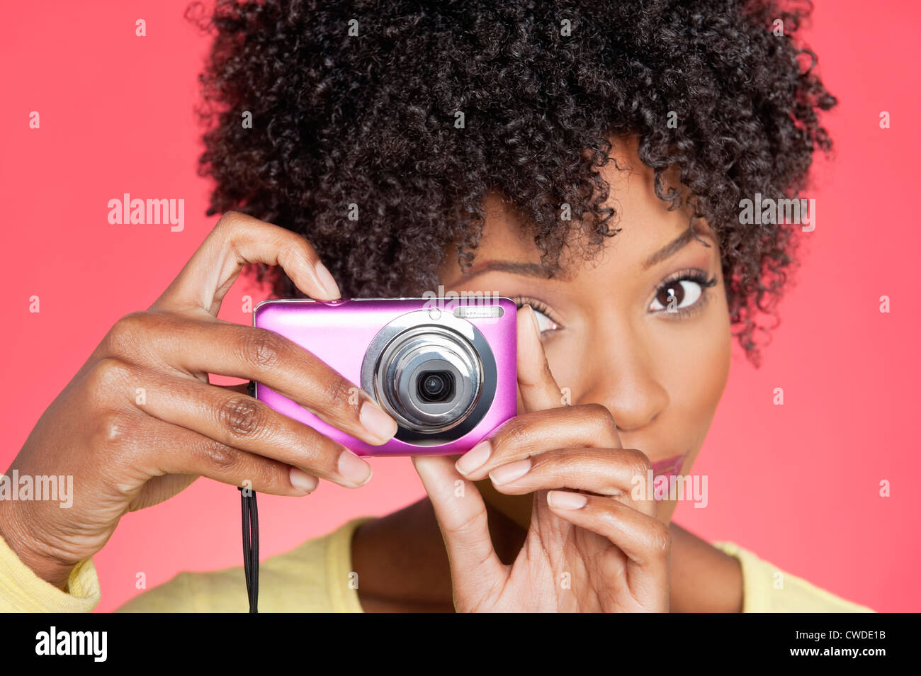 Portrait of an African American woman taking picture from camera over colored background Stock Photo