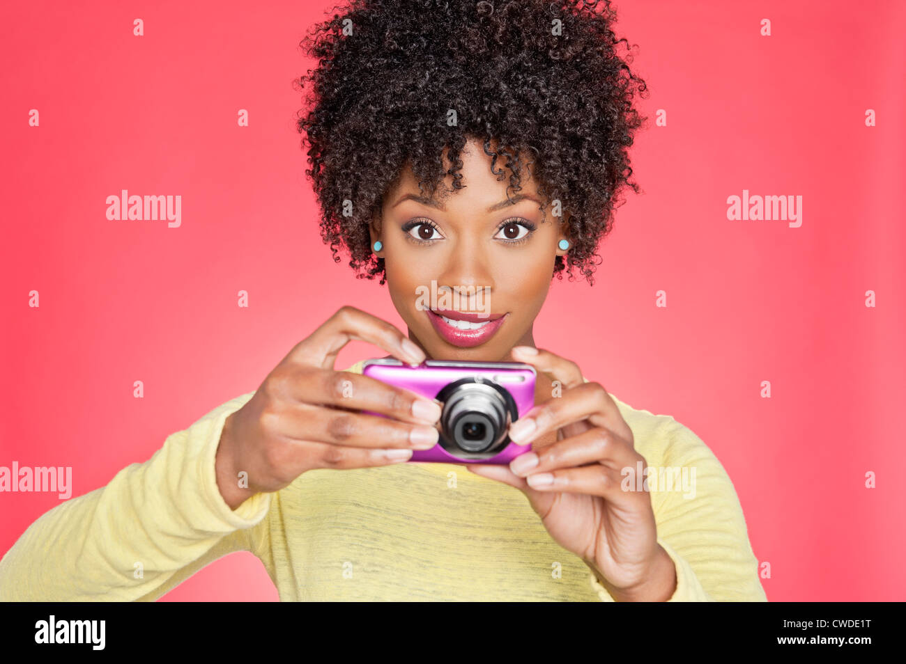 Portrait of an African American woman holding a camera over colored background Stock Photo