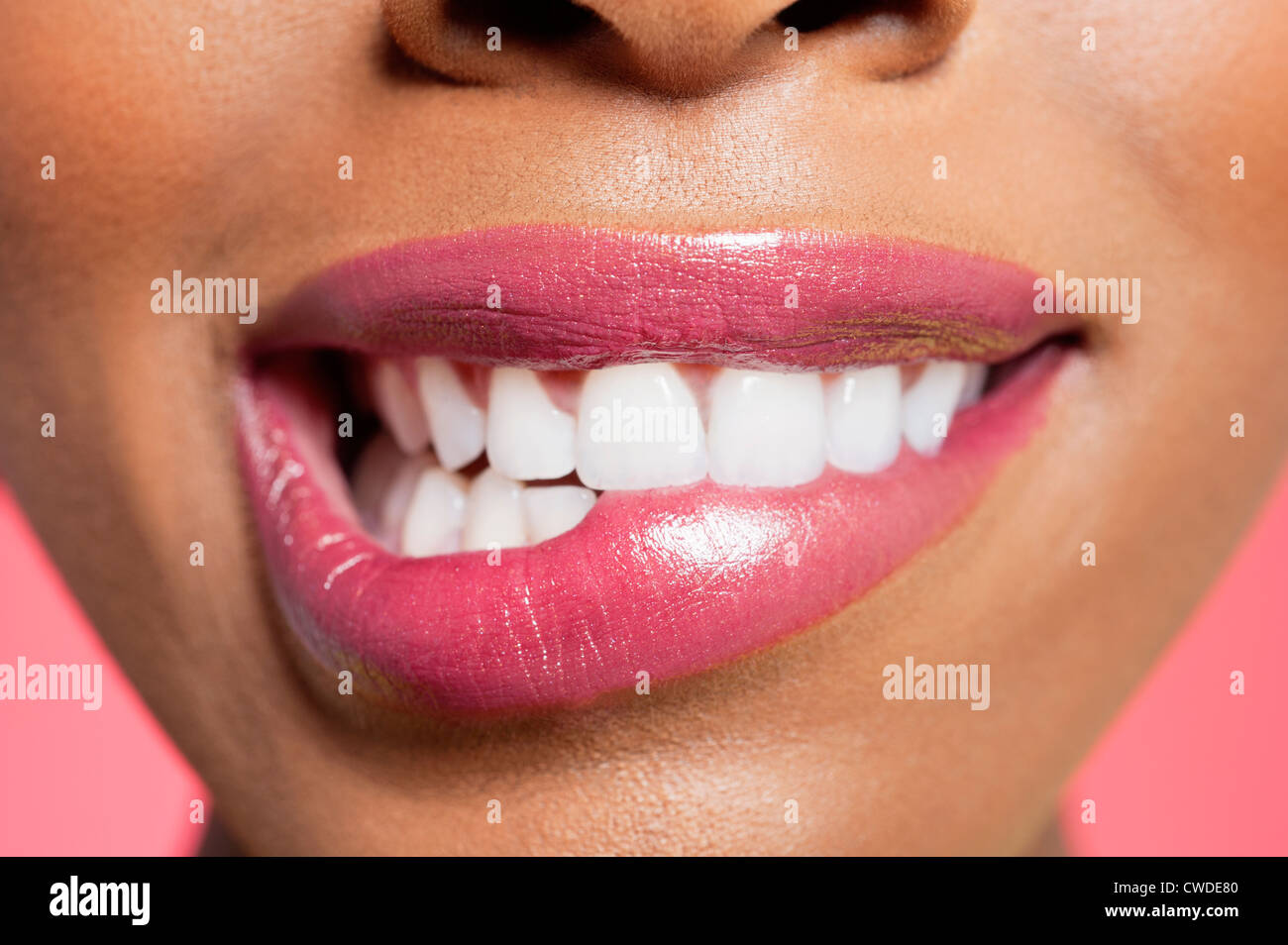 Close-up view of an female biting her lip over colored background Stock Photo