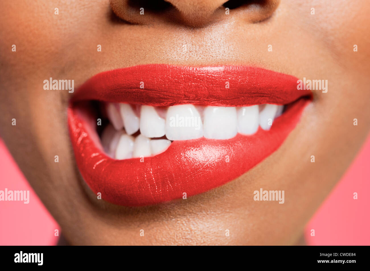 Close-up view of an female biting her red lip over colored background Stock Photo