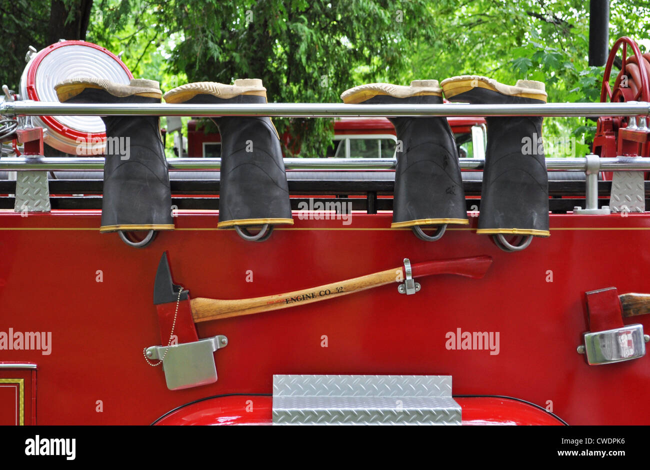 The bright red and chrome of a classic fire engine provide a colorful background for the fire fighter's safety equipment. Stock Photo