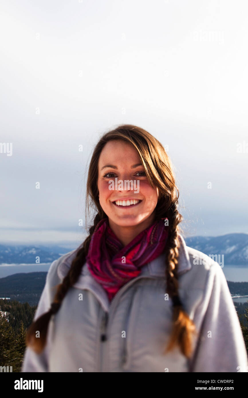 A beautiful young woman smiling stops for a portrait on a winter hike in Idaho. Stock Photo