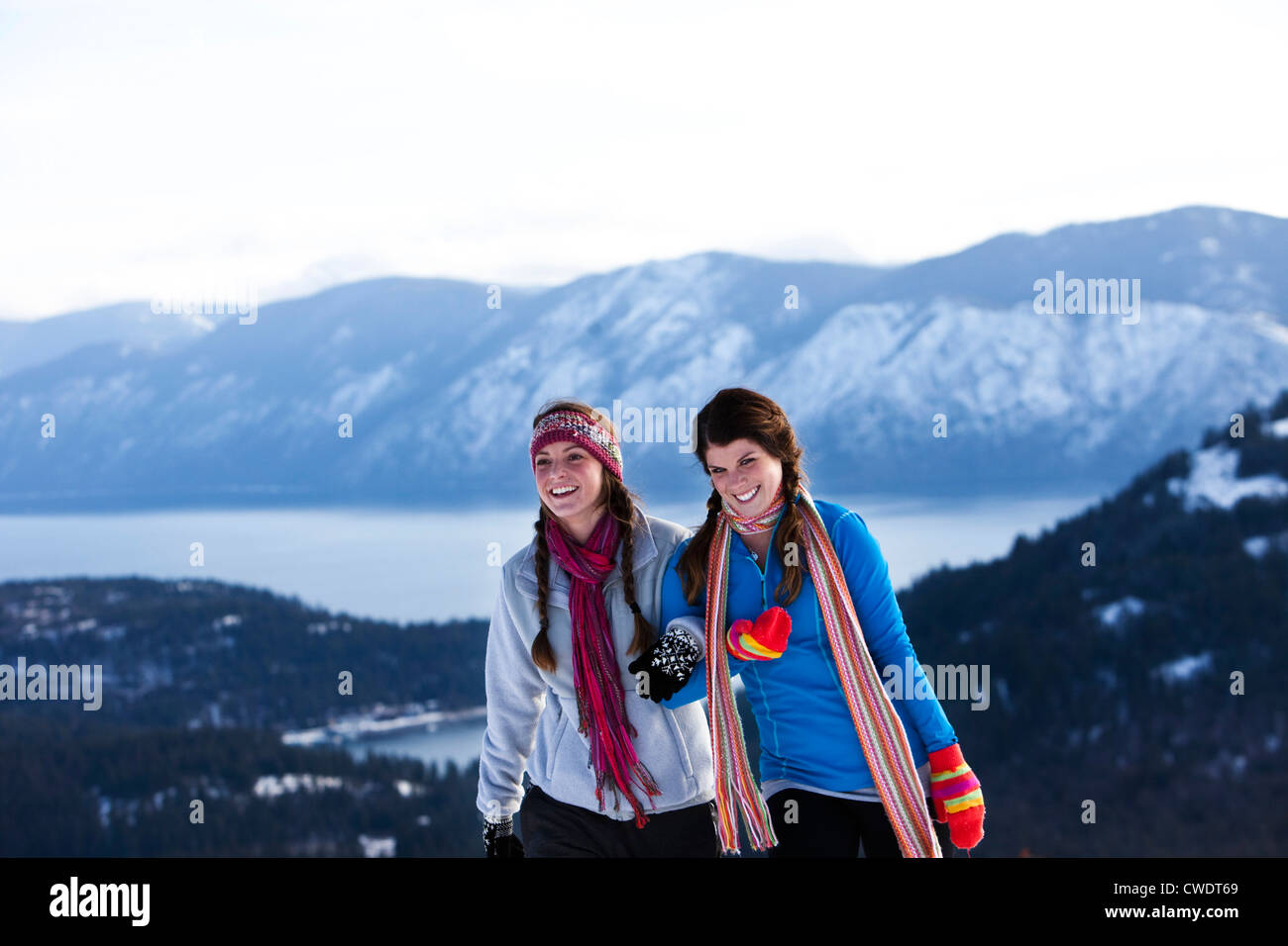 Two athletic young women laugh and smile while hiking on a winter day in Idaho. Stock Photo