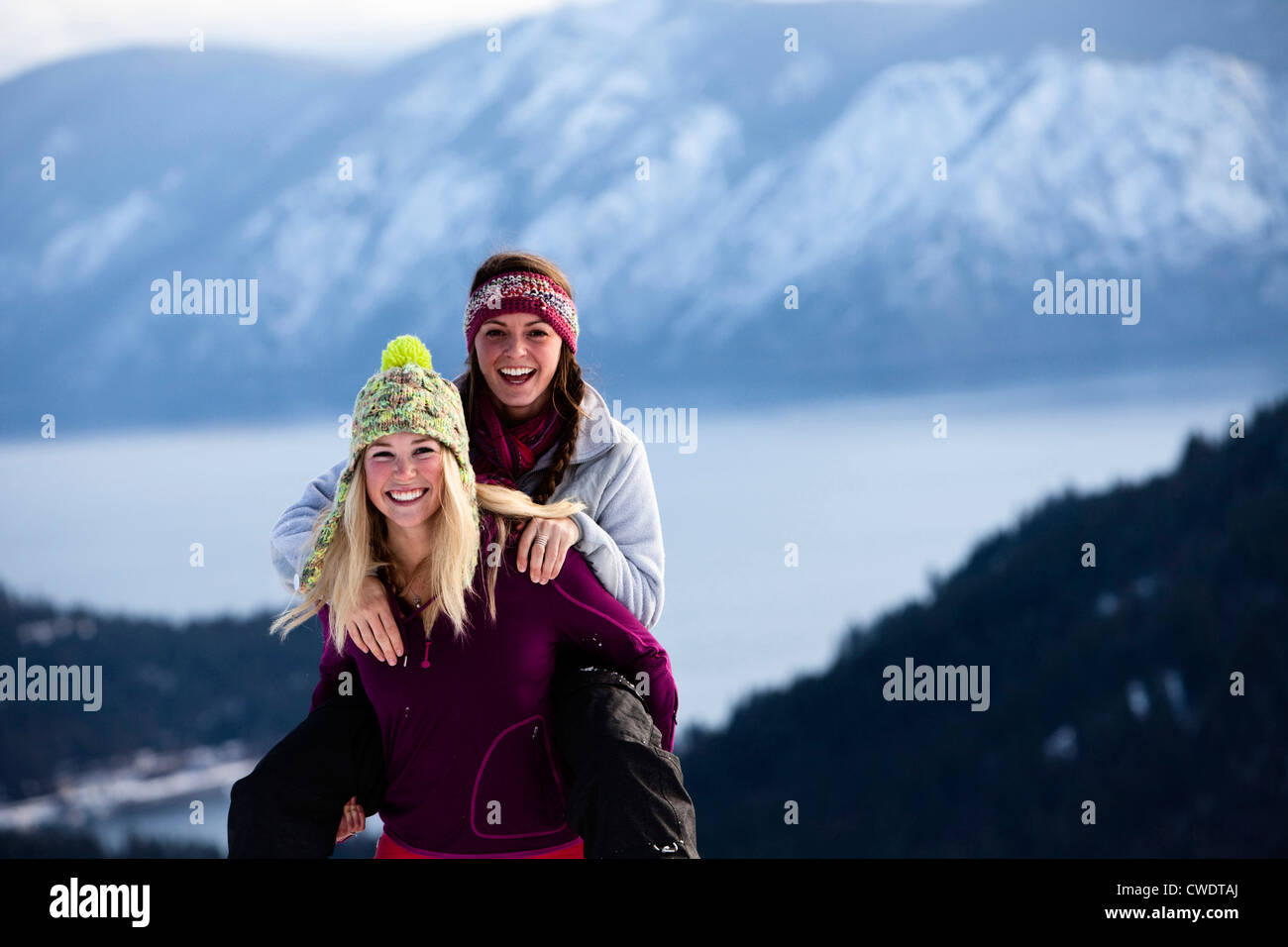 Two athletic young women laugh and smile while hiking on a winter day in Idaho. Stock Photo
