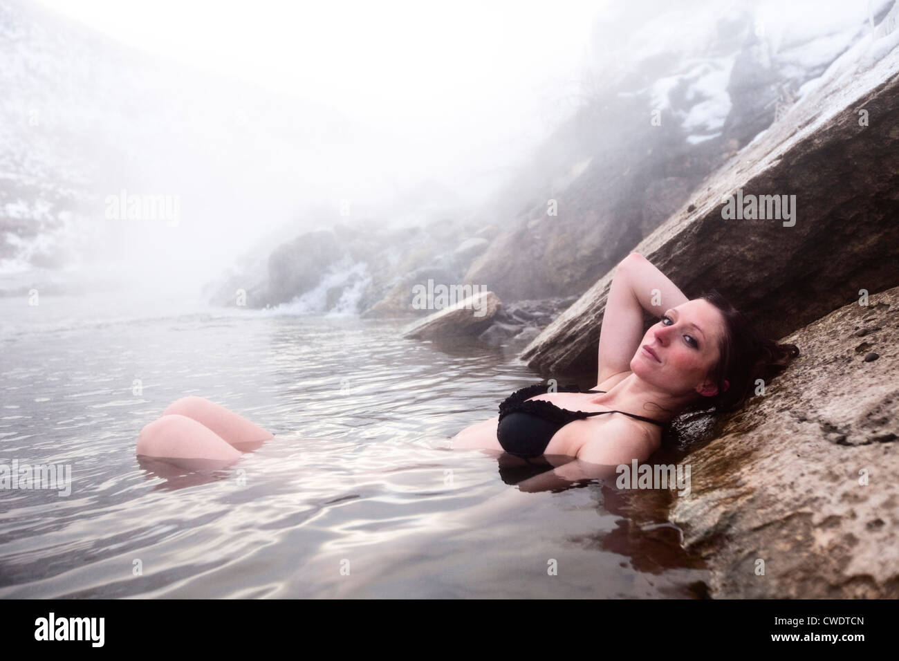 A beautiful woman relaxing in a hot springs waterfall in Montana. Stock Photo