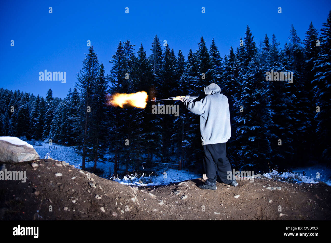 A young man shooting a large gun with a flame coming out of the barrel in Montana. Stock Photo
