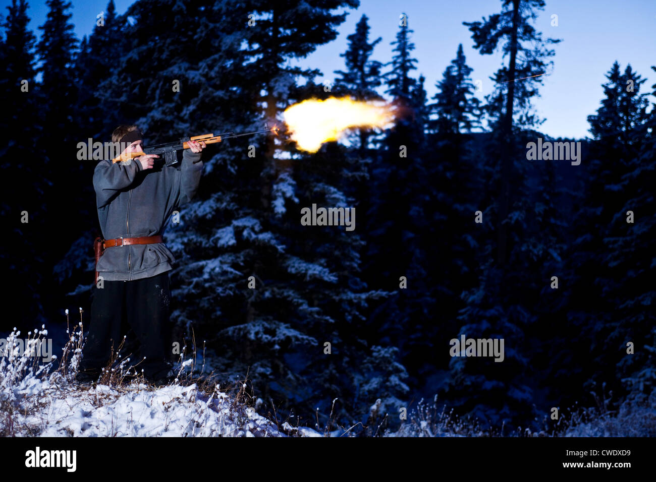 A young man shooting a large gun with a flame coming out of the barrel in Montana. Stock Photo