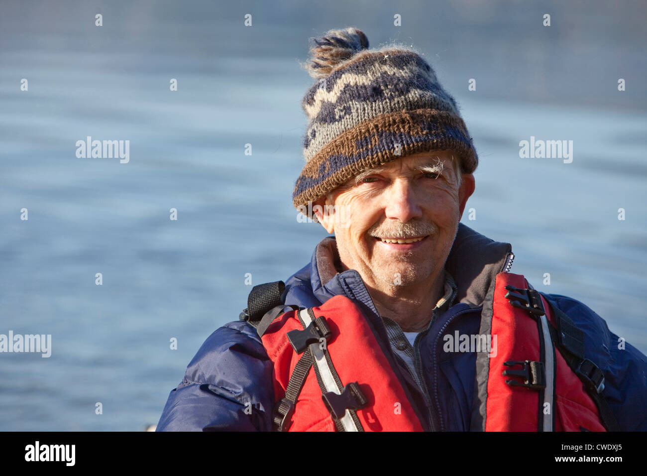 A athletic retired man smiling at the camera while kayaking on a lake in Idaho. Stock Photo