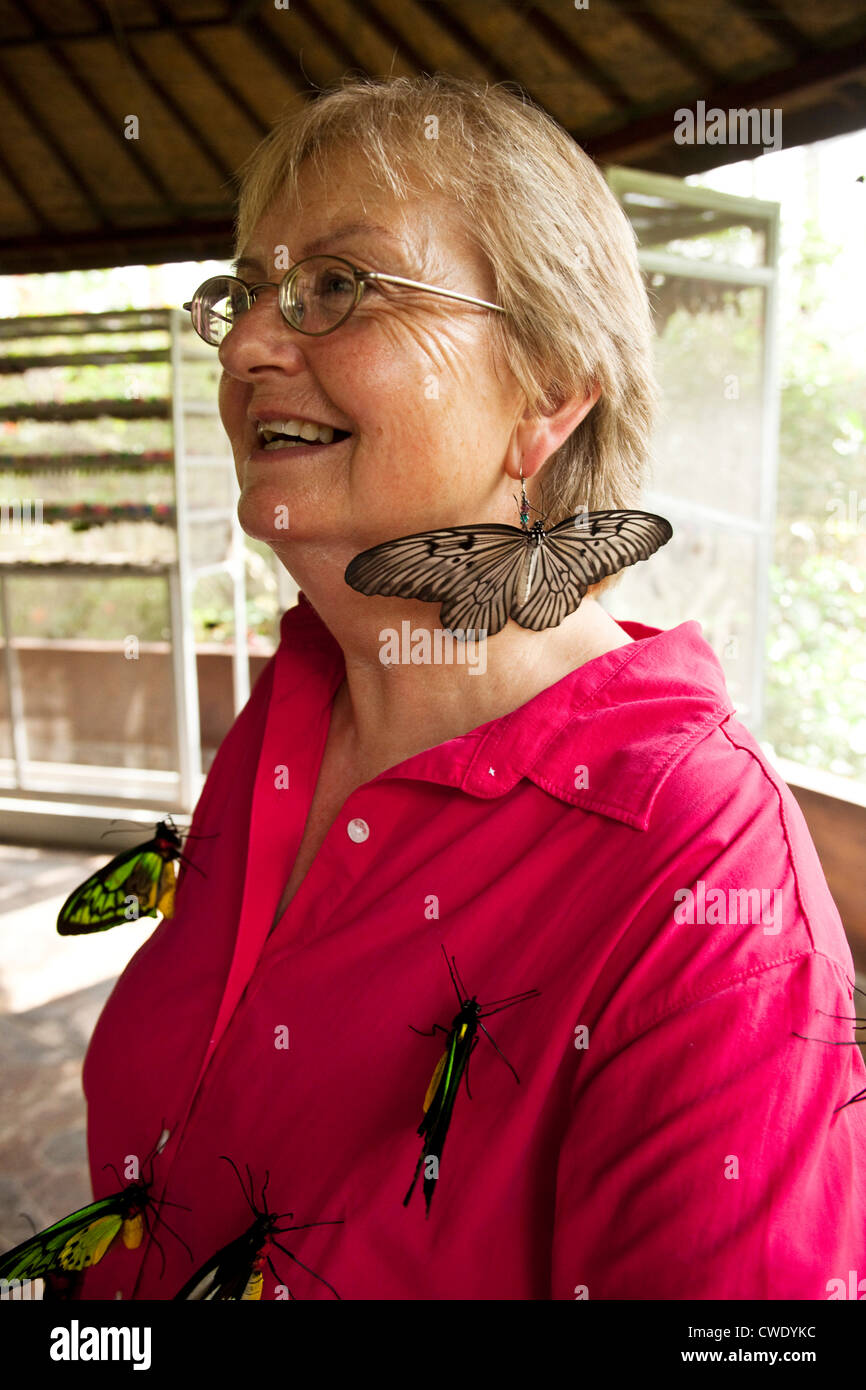 A retired woman smiling while covered in huge butterflies in Bali, Indonesia. Stock Photo
