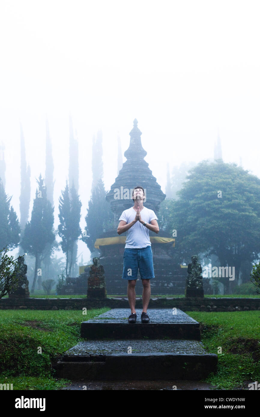 A man standing on the steps of a temple meditates with a foggy background in Bali, Indonesia. Stock Photo