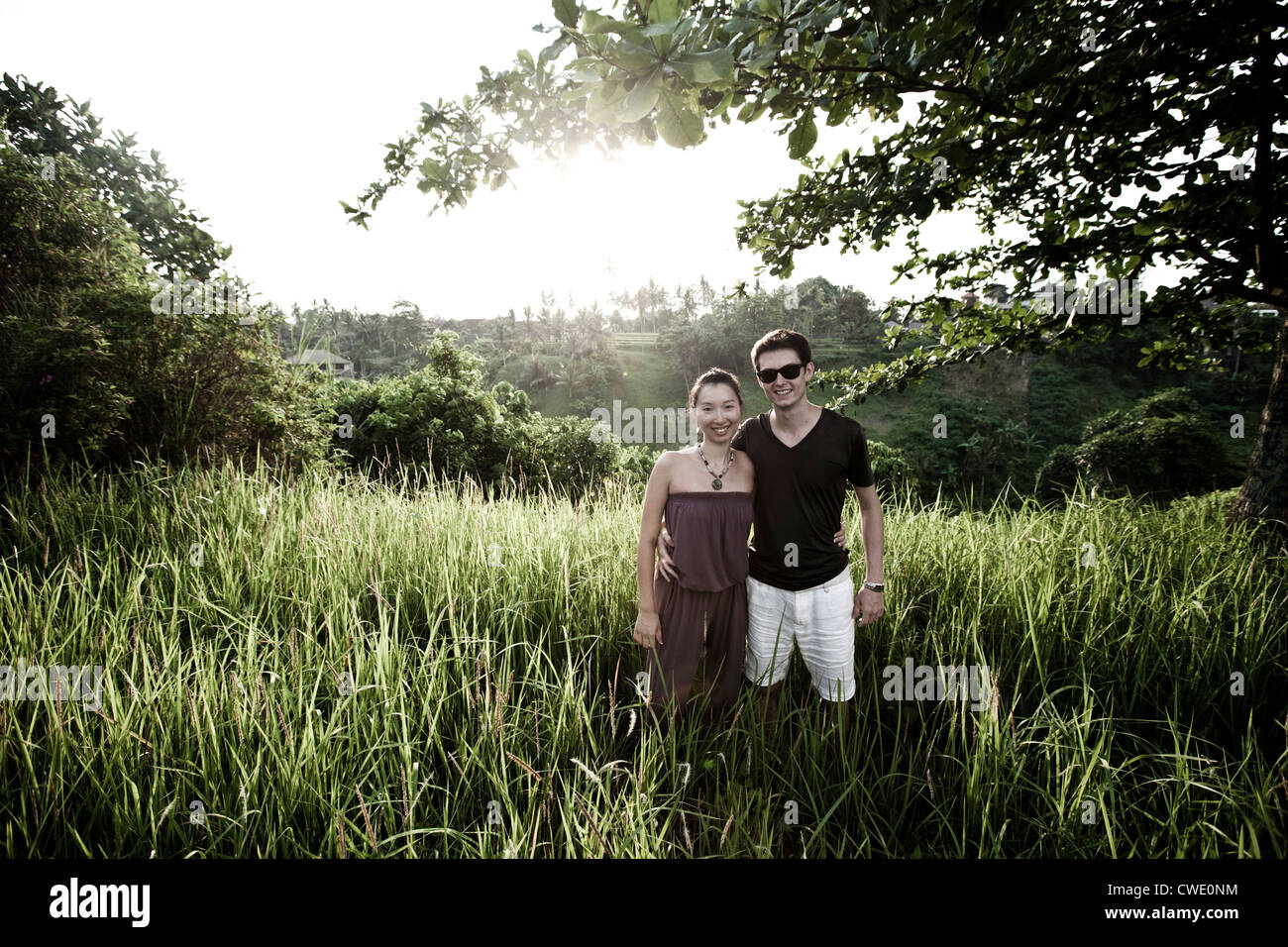 A happy married couple holding hands and walking in a lush jungle setting in Bali, Indonesia. Stock Photo