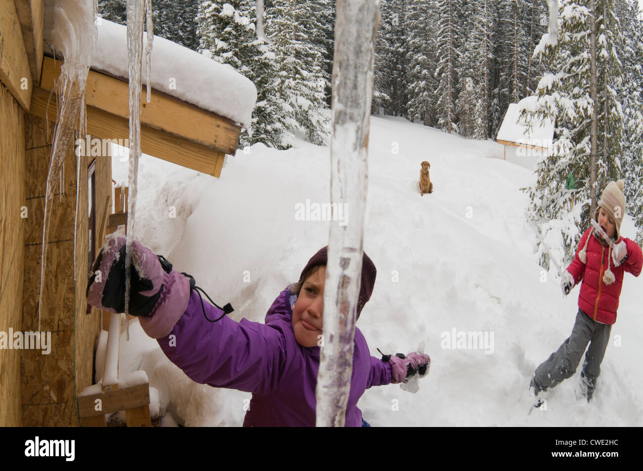 Two Young Girls Breaking Icicles Off Of A Cabin Roof Nearg Molas