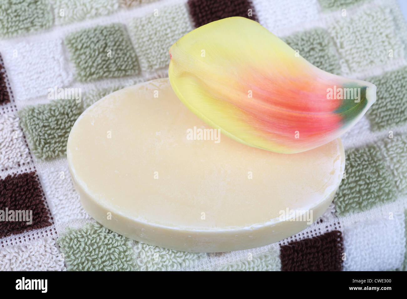 A bar of homemade soap with a tulip petal on a terry cloth towel. Stock Photo