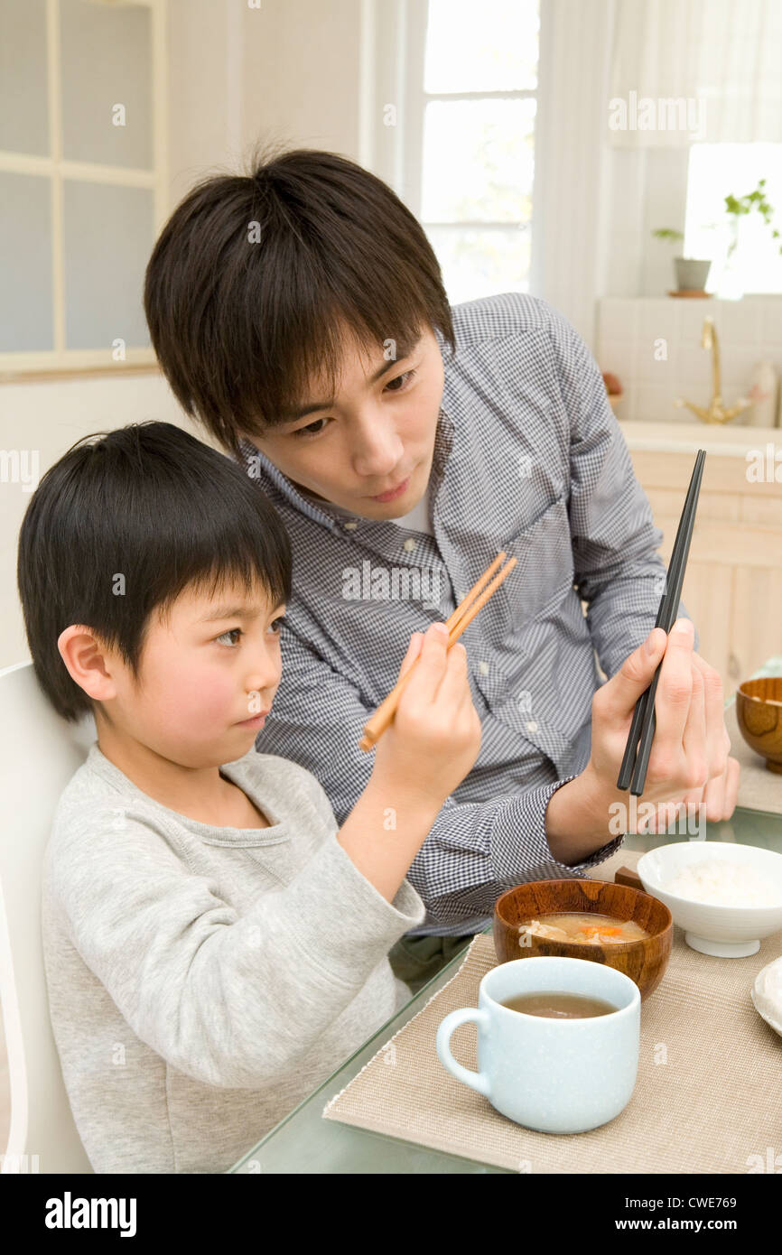 Father teaching son how to use chopsticks Stock Photo