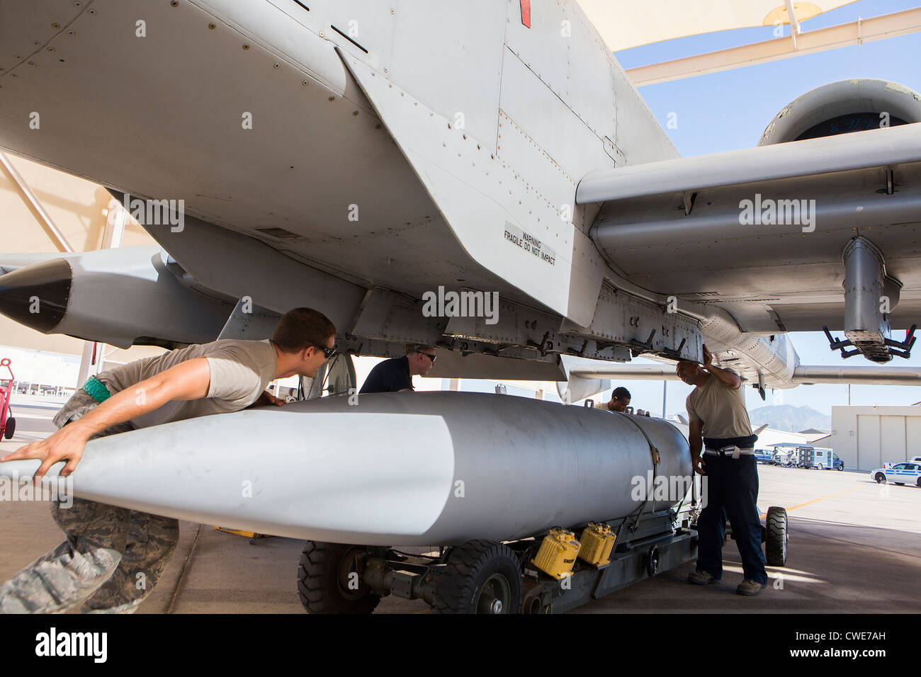 Airmen attach a external fuel tank to an A10 Thunderbolt from the