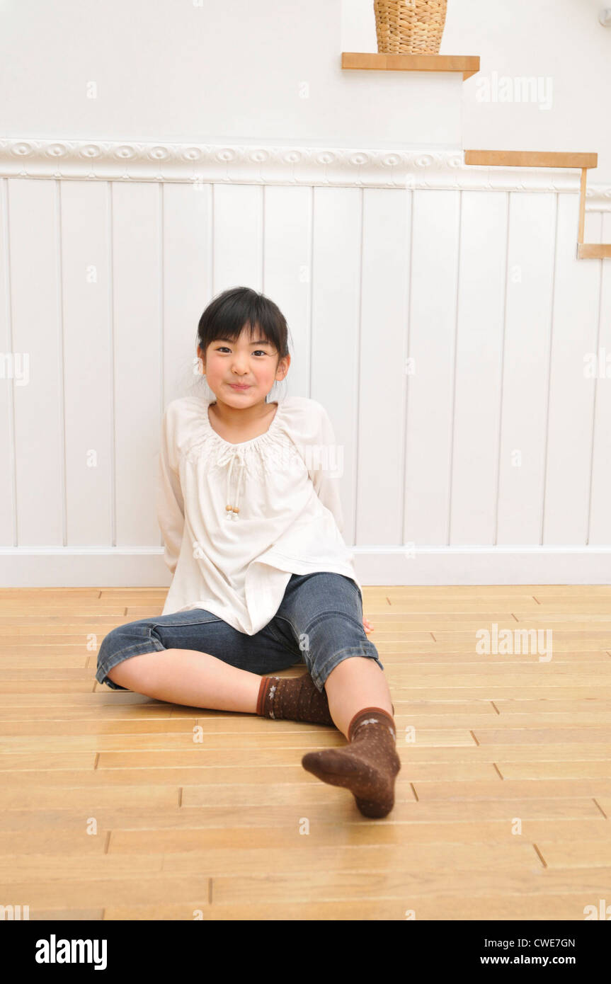 Girl sitting on wooden floor Stock Photo - Alamy