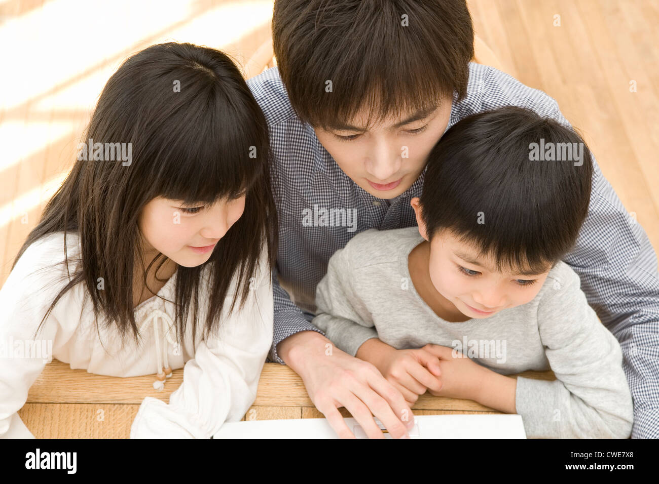 Father using laptop with two children Stock Photo - Alamy