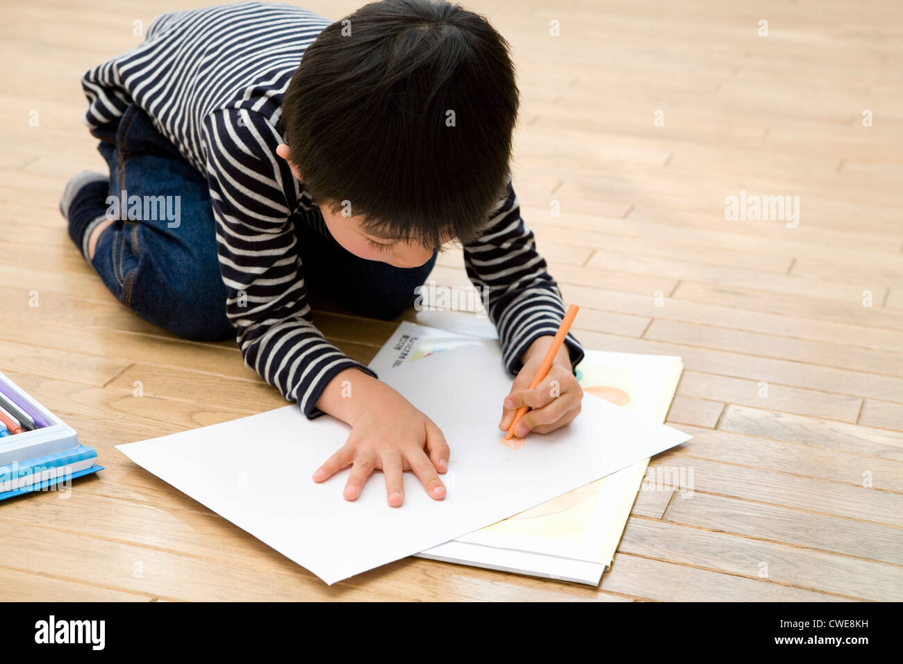 Boy kneeling and drawing picture Stock Photo Alamy