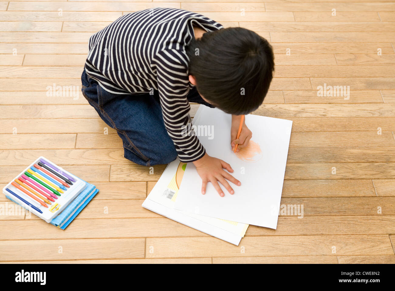 Boy kneeling and drawing picture Stock Photo Alamy